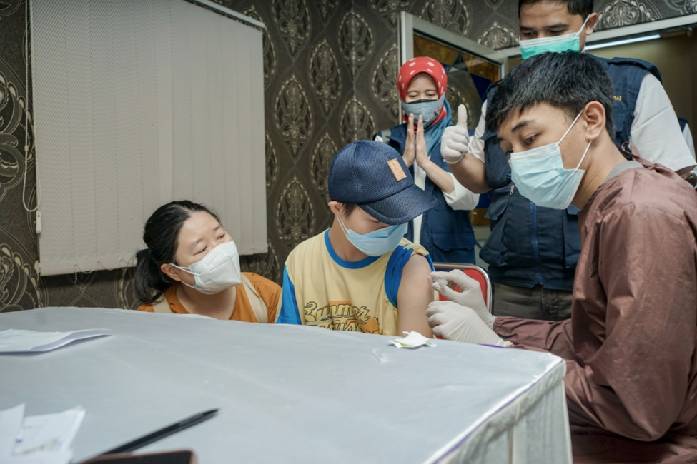 Medical staff cheer on as a child gets his Covid-19 vaccine shot.